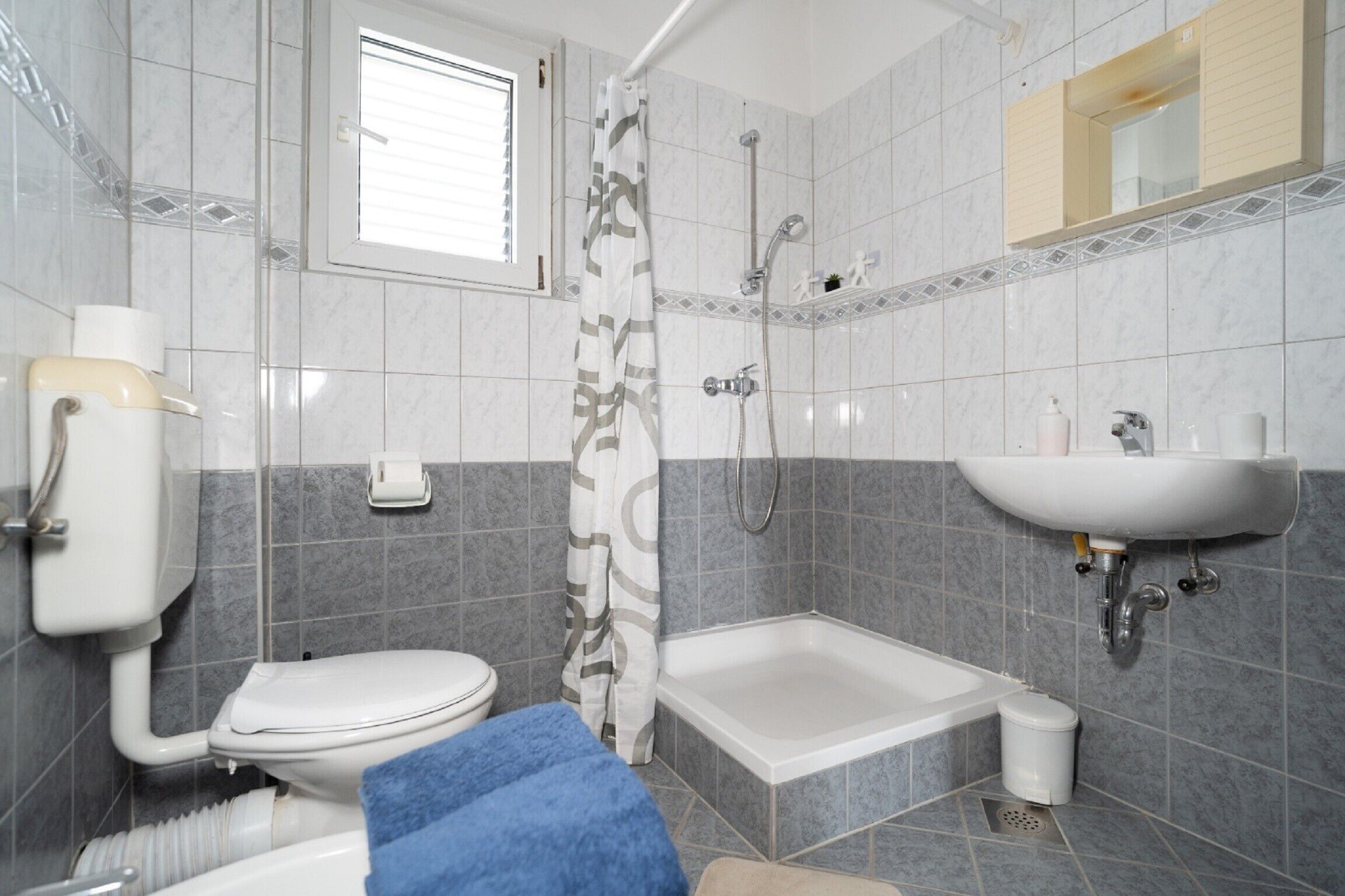 A bathroom with a toilet, shower, and sink.