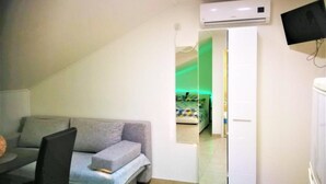 Una habitación compacta con sofá, una mesita pequeña y un armario con espejo.