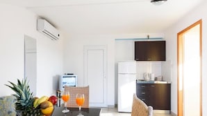 Una cocina moderna con armarios oscuros, un refrigerador blanco y un televisor pequeño sobre un soporte.