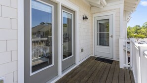 Et hus med veranda, hvid facade og træterrasse.
