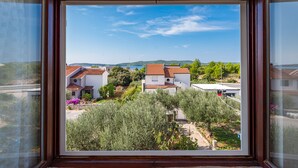Vista desde una ventana que da a una zona residencial con casas, vegetación y cielo despejado.