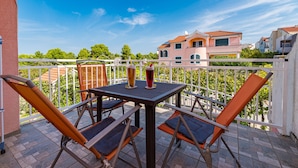 Ein Balkon mit Tisch und Stühlen, der auf ein Wohngebiet mit Häusern und Bäumen blickt.