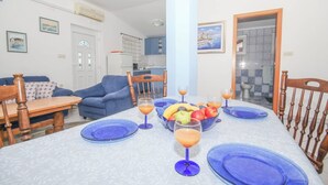 Un coin repas avec une table dressée pour deux personnes, des assiettes bleues et des verres de jus d’orange.