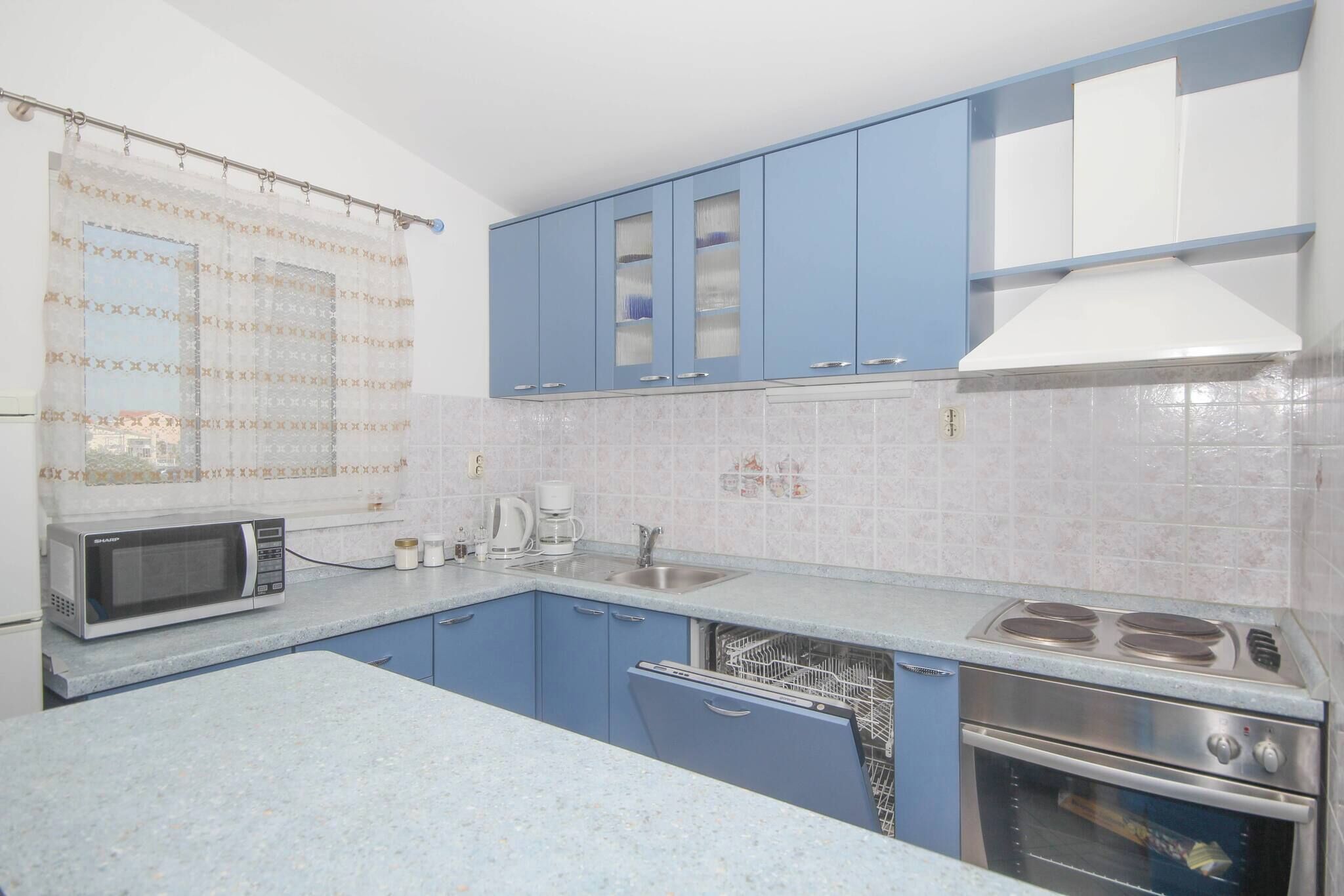 A kitchen with blue cabinets, a microwave, a coffee maker, a sink, and a stove.