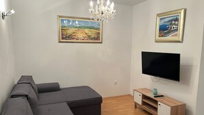 Una sala de estar moderna con un sofá modular, un televisor de pantalla plana, un mueble de madera y dos cuadros enmarcados en las paredes.