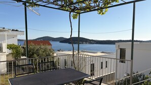 Un balcón con mesa y sillas, con vistas a una masa de agua y colinas.