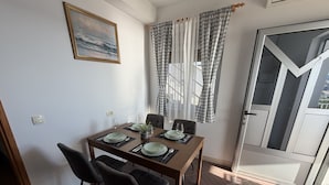 Un comedor con una mesa dispuesta para cuatro personas, sillas, un cuadro en la pared y una puerta con vistas.