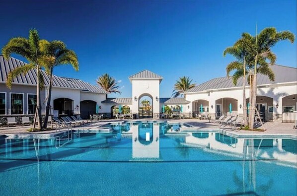Relax by the resort pool surrounded by palm trees and lounge chairs.