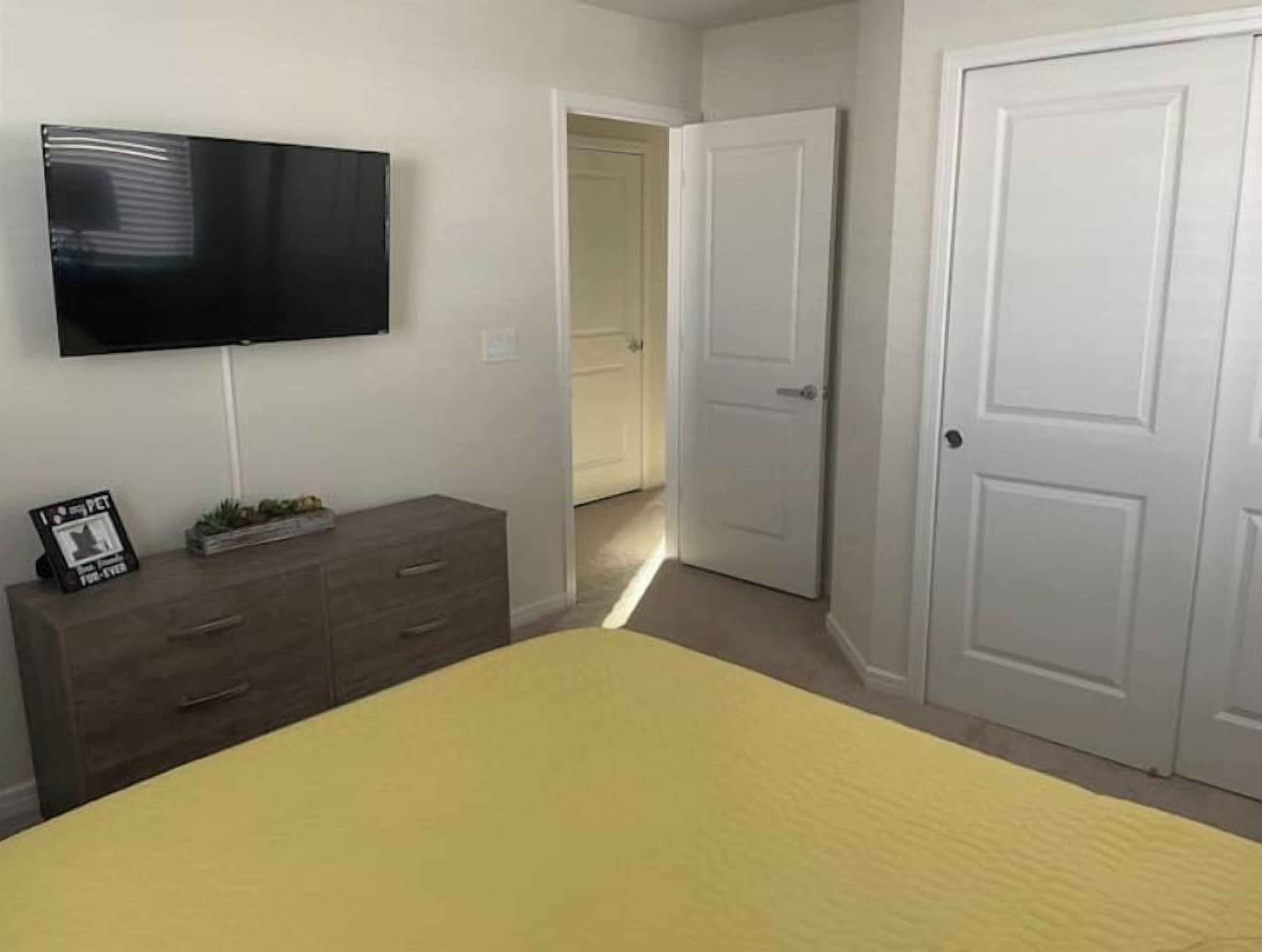 Un dormitorio con una cama, un aparador, un televisor y una puerta.