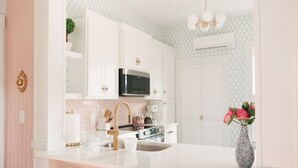 A modern kitchen with white cabinetry, a stainless steel microwave, and a white countertop.