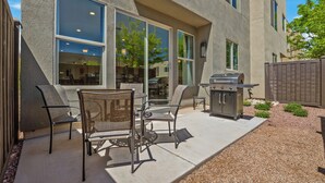 Patio esterno con barbecue, sedie e vista sull'interno.