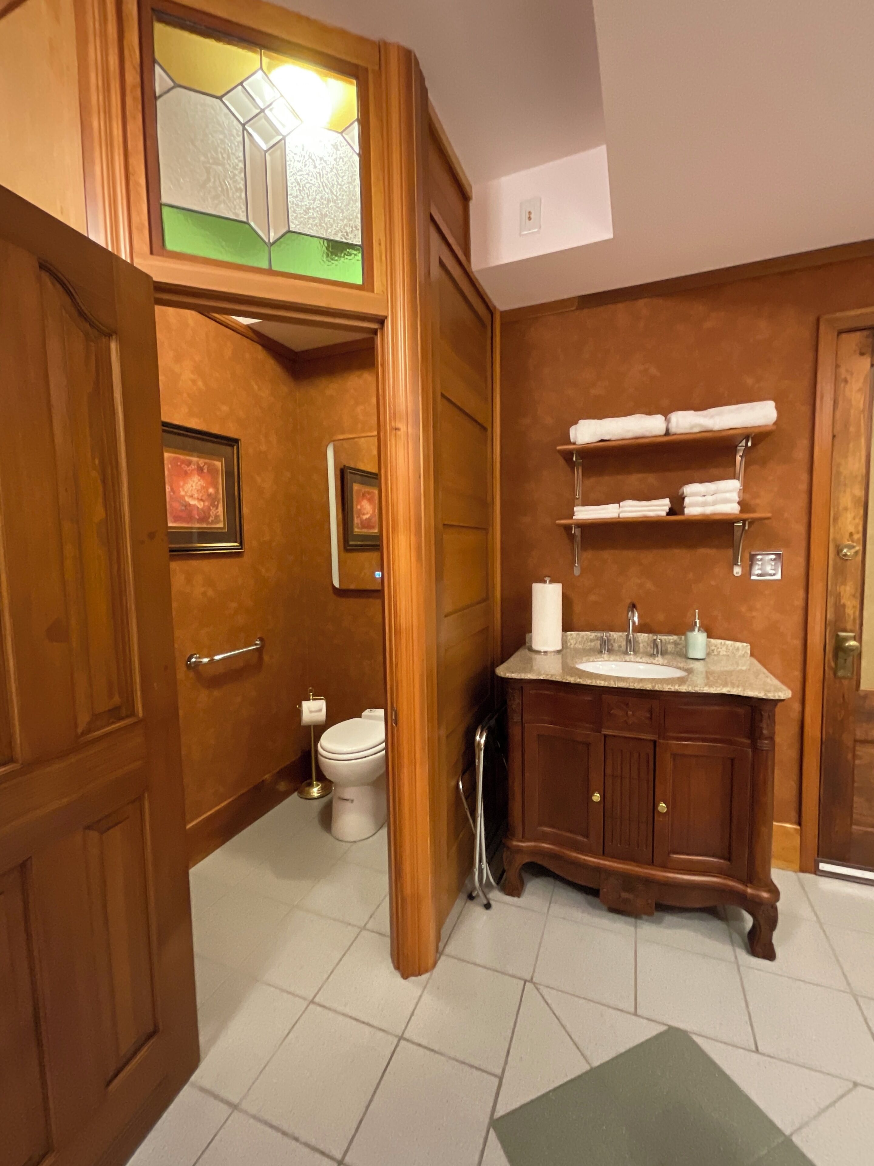 A wooden bathroom with a toilet, sink, and towel rack.