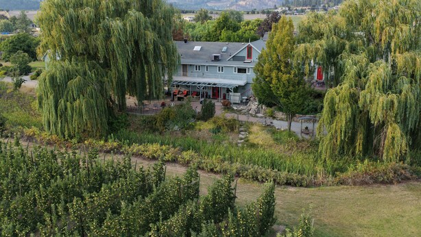Een huis met een grote tuin, omringd door bomen en uitzicht op het platteland.