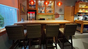 Een keuken met een centraal eiland, barstoelen, houten kastjes en hanglampen.