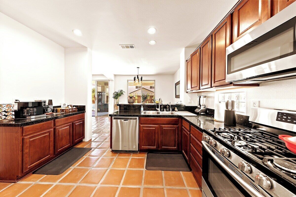 A modern kitchen with wooden cabinets, a stainless steel dishwasher, a gas stove, and a large island with a sink.