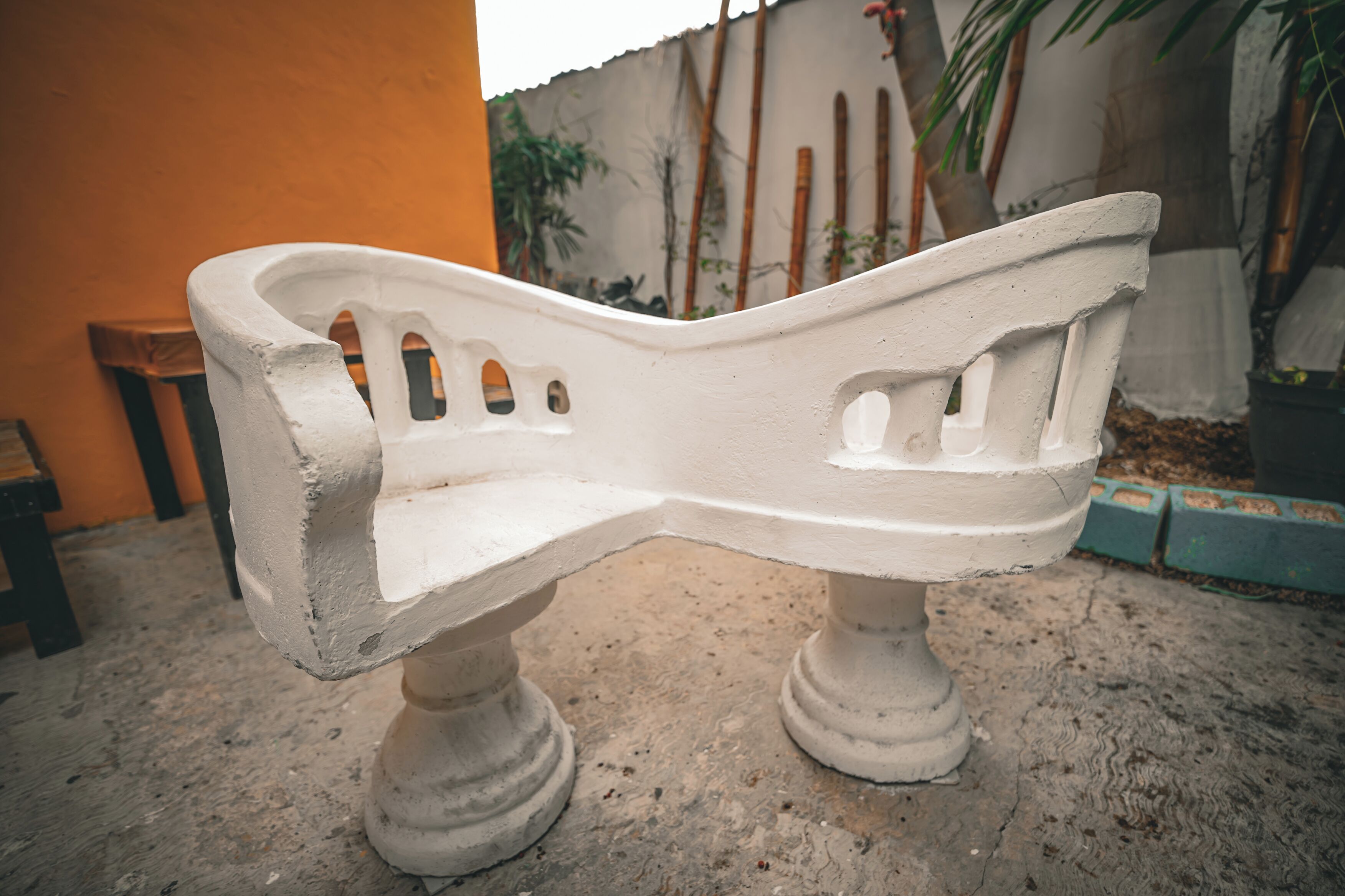 A white bench with a curved backrest, placed on a concrete surface.