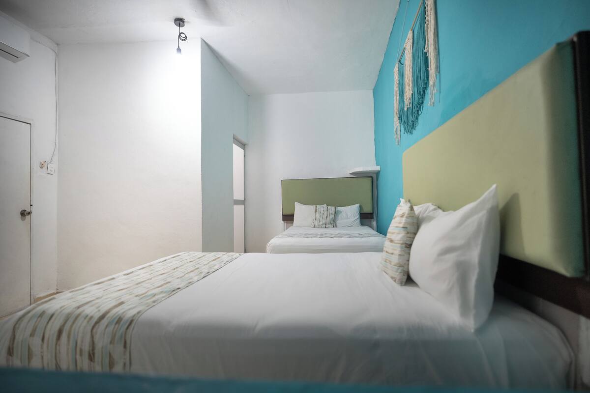 A hotel room with a large bed, a smaller bed, and a headboard with a decorative design.