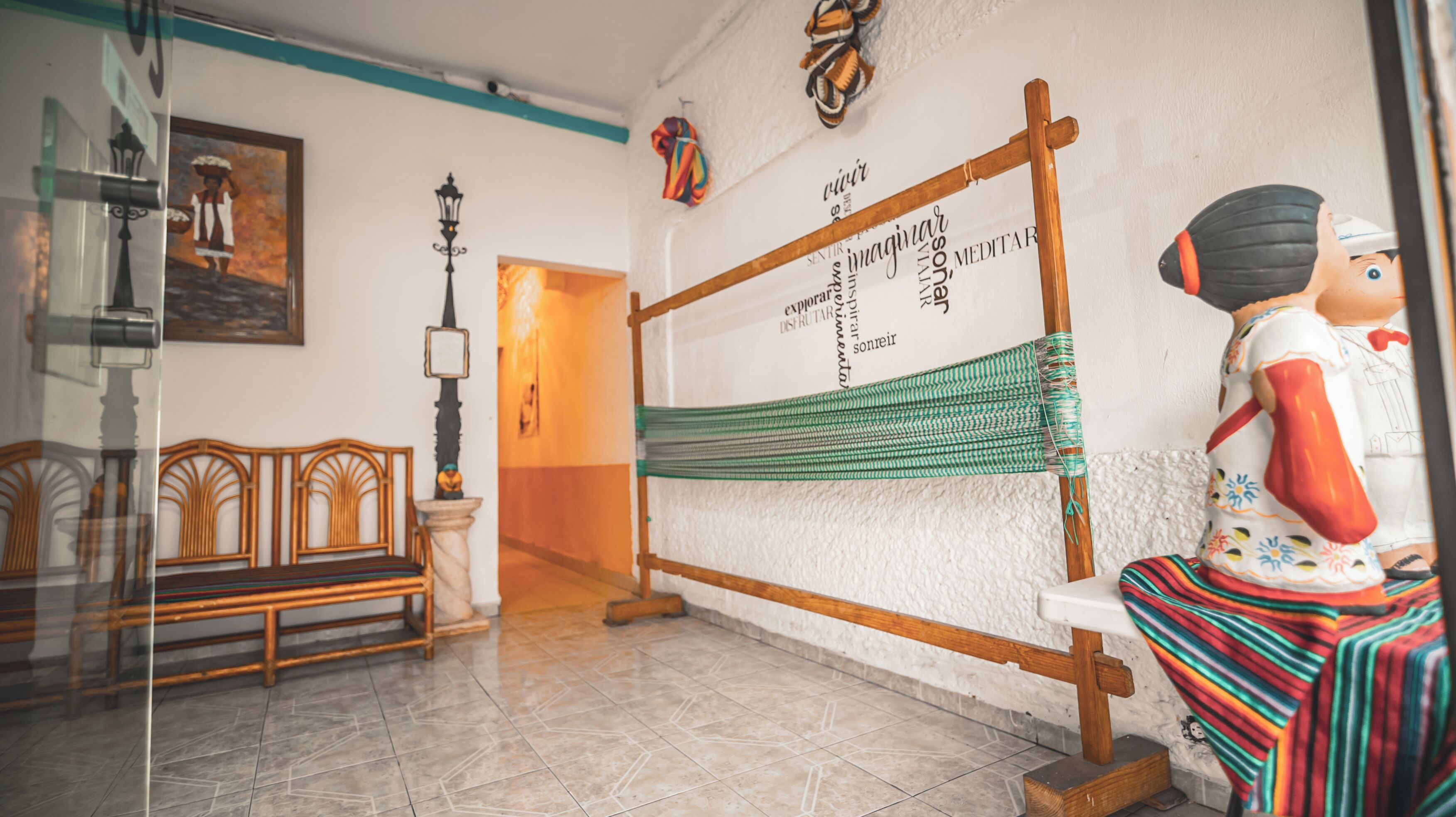 Una habitación con un tapiz tejido, un banco de madera y una estatua.