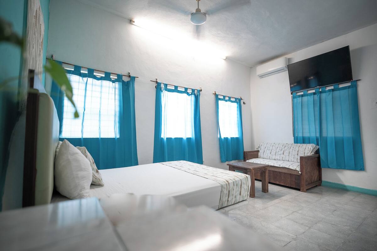 A bedroom with a bed, a wooden sofa, and a small table.
