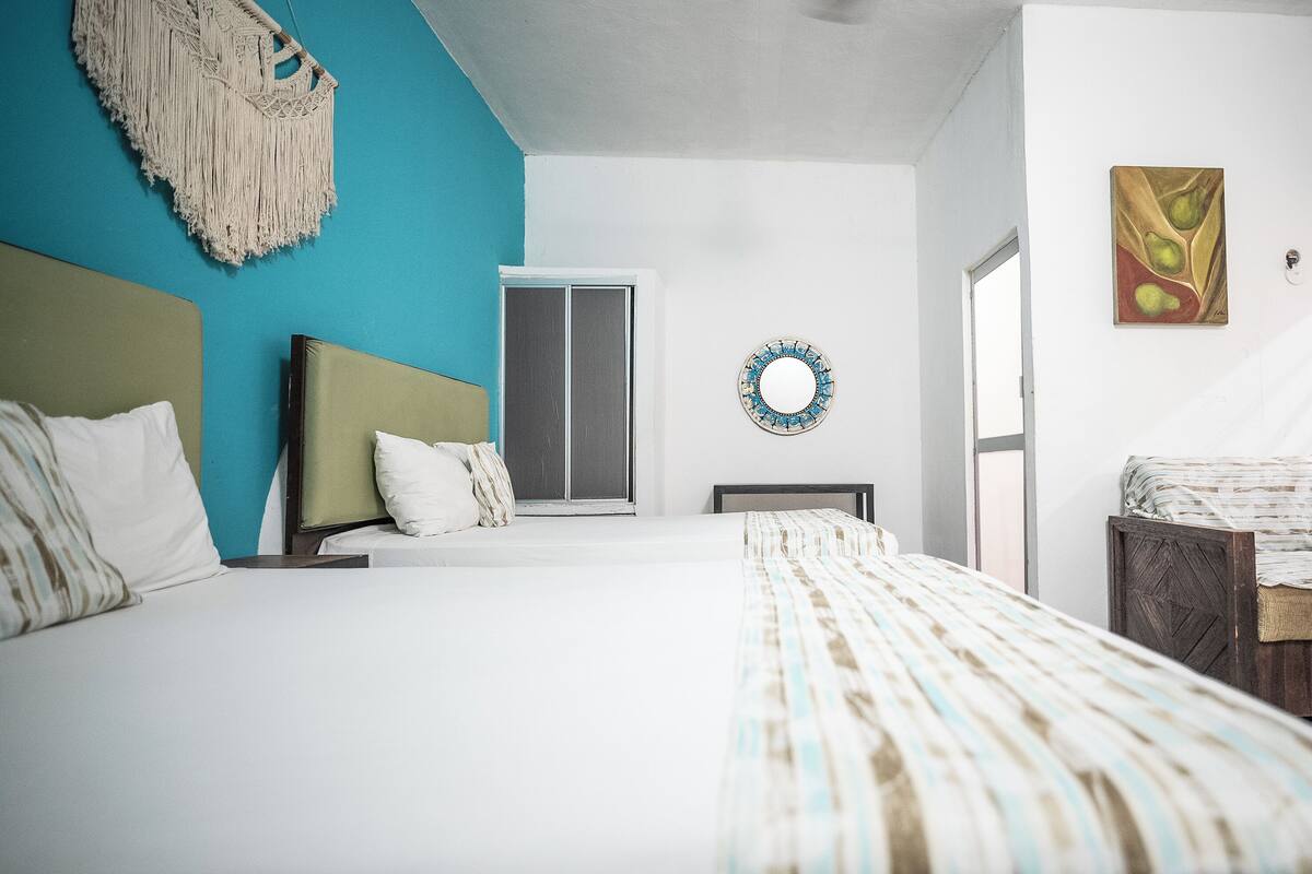 A bedroom with a bed, a chair, a wall-mounted mirror, and a door.