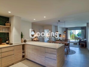 A modern kitchen with a central island, wooden cabinets, and a dining area with a table and chairs.
