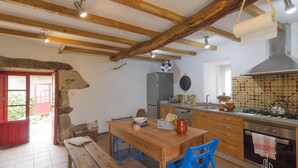 A rustic kitchen with wooden beams, a refrigerator, stove, and a dining table with chairs.