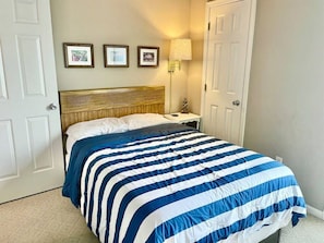 Quarto com cama, quadros nas paredes, mesa de cabeceira e abajur.