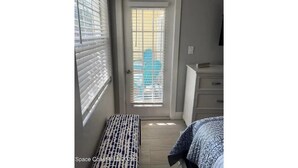 A narrow hallway with a bench, a door with blinds, and a dresser.