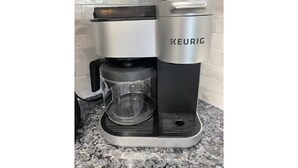 A Keurig coffee machine with a glass carafe and a drip tray on a granite countertop.