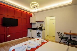A compact hotel room with a bed, a flat-screen TV, a washing machine, a microwave, and a small kitchenette. - St.Moscow Suite Taksim (Istanbul)