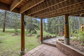 Guests can enjoy a serene outdoor space with a covered area and a wooden deck overlooking the surrounding landscape.