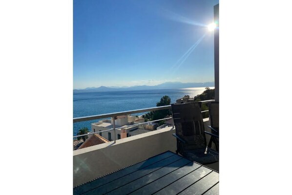 Enjoy breathtaking views of the sea from this balcony with a bathtub and two chairs.