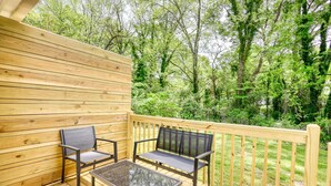 A wooden deck with two chairs and a table, surrounded by a wooden railing, overlooking a forested area. - Sweet Magnolias Home: Walk to Square (Covington)