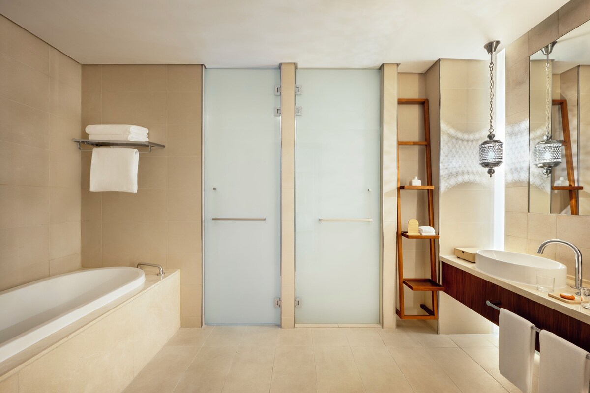 A modern bathroom with a bathtub, a glass shower enclosure, and a vanity with a sink and mirror.
