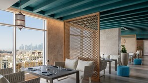 Un comedor moderno con vistas a la ciudad, separadores de madera y mobiliario contemporáneo.