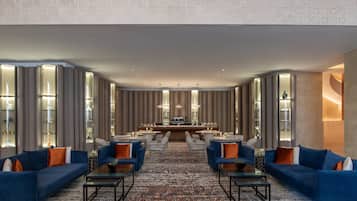 A spacious hotel lobby with a central bar area, seating arrangements, and decorative lighting.