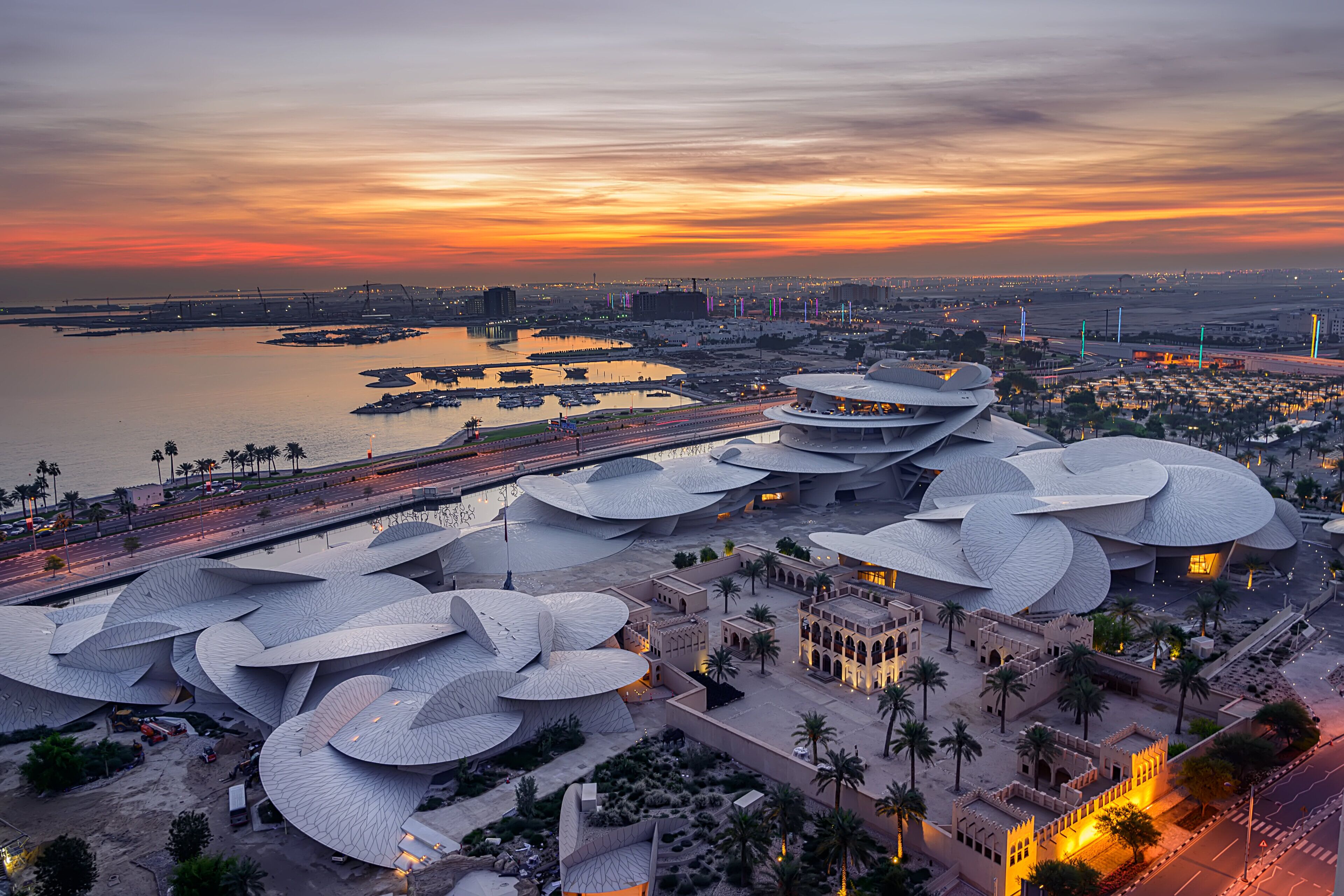 A modern architectural complex with multiple domed structures, a waterfront, and a bridge connecting different areas.
