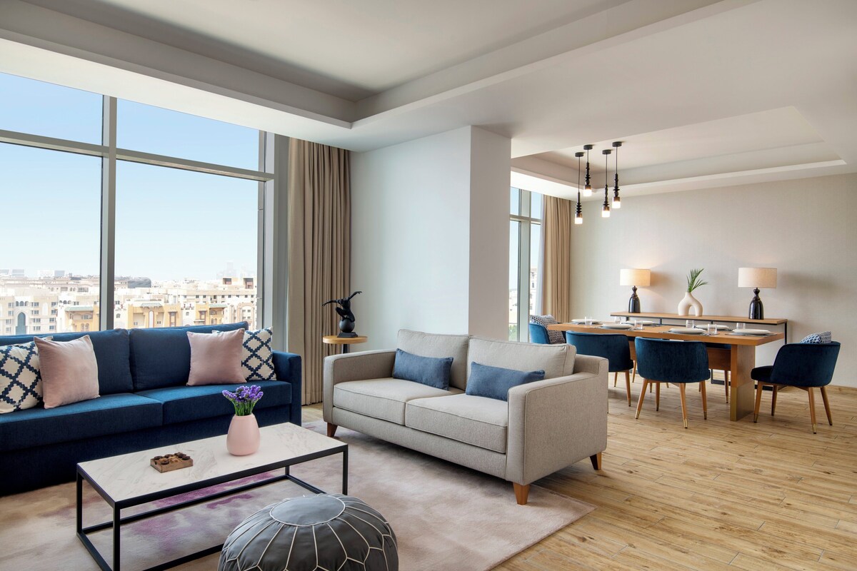 A modern living room with a sofa, coffee table, and dining area.
