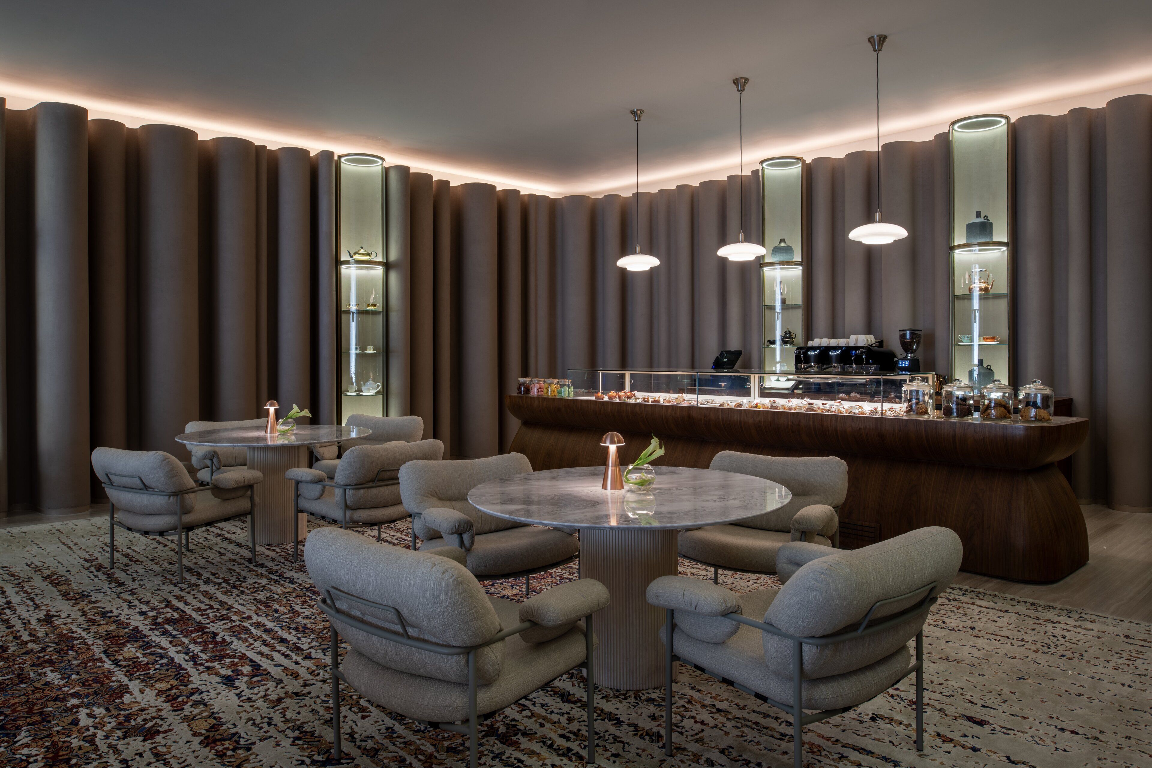 Een moderne hotellobby met een ronde eettafel, zachte zitplaatsen, een bar en een kamerbreed tapijt met een patroon.