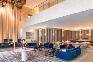 A spacious lobby with blue sofas, a round coffee table, and a bar area. - Abesq Doha Hotel and Residences - An IHG Hotel (Doha)