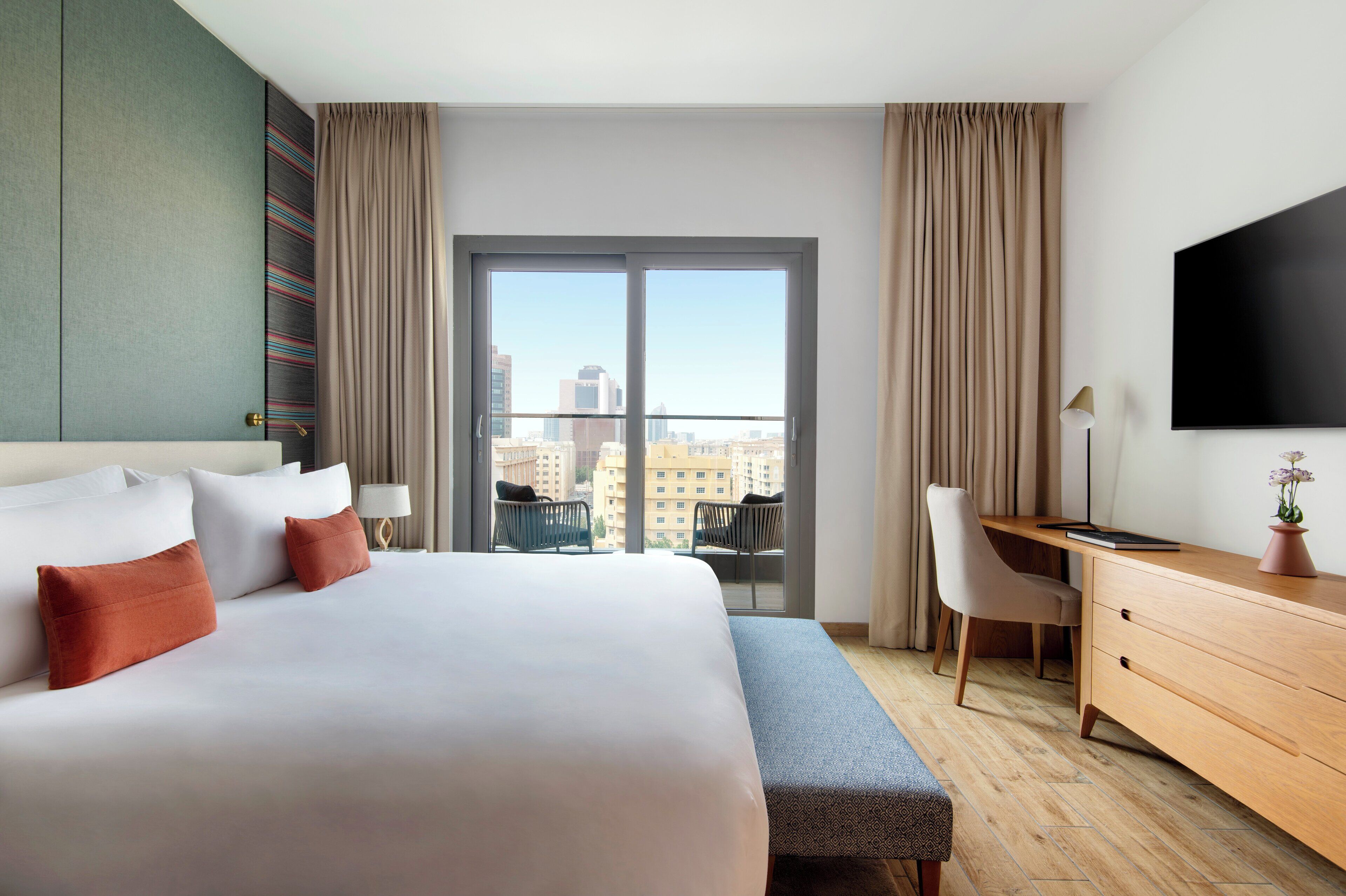 Een hotelkamer met een groot bed, een bureau, een stoel en een televisie aan de muur.