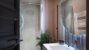 A modern bathroom with a glass shower enclosure, a large sink with a mirror, and a potted plant. - Notre-Dame 3* - OG IMMO (Annecy)