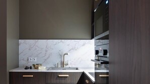 A modern kitchen with dark wood cabinets, a marble backsplash, and stainless steel appliances. - Notre-Dame 3* - OG IMMO (Annecy)