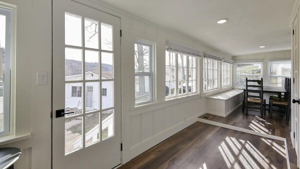 Una habitación amplia con ventanas grandes, un banco incorporado y una zona de comedor con sillas.