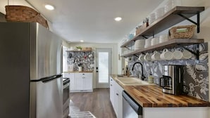 Una cocina moderna con refrigerador de acero inoxidable, encimera de madera y una máquina de café.
