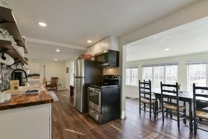A modern kitchen with a built-in oven, microwave, and refrigerator. There is a dining area with a table and chairs.