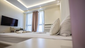 A modern hotel room with a large bed, a flat-screen TV mounted on the wall, and a desk with a chair. - Apartments Royal - Arcadia Building (Belgrade)