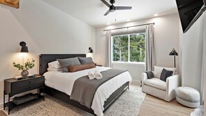 A bedroom with a bed, bedside table, lamp, window, and ceiling fan.