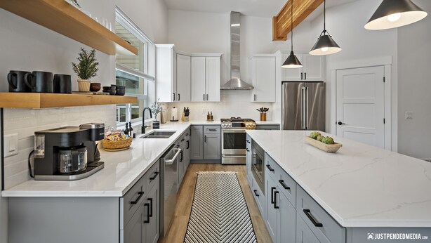 A modern kitchen with white cabinets, stainless steel appliances, and a large island.