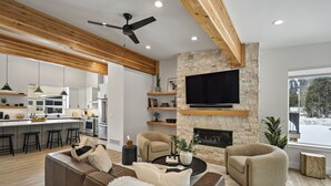 A modern living room with a fireplace, a large TV, and a cozy seating area.